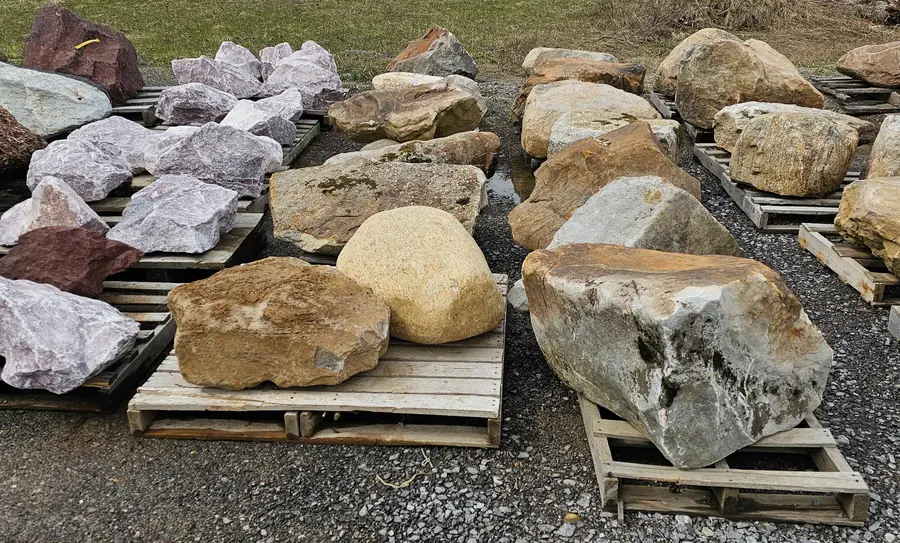 Rows of decorative boulders on pallets: pink, red, tan and grey stone