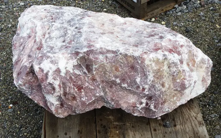 A pink and white marbled boulder on a pallet