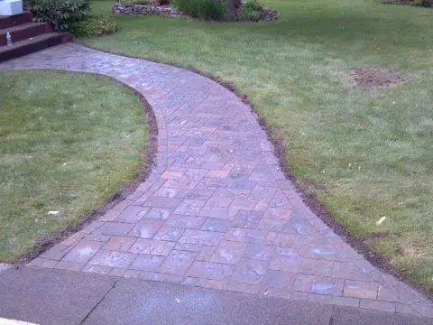 A curved paver walkway across a lawn
